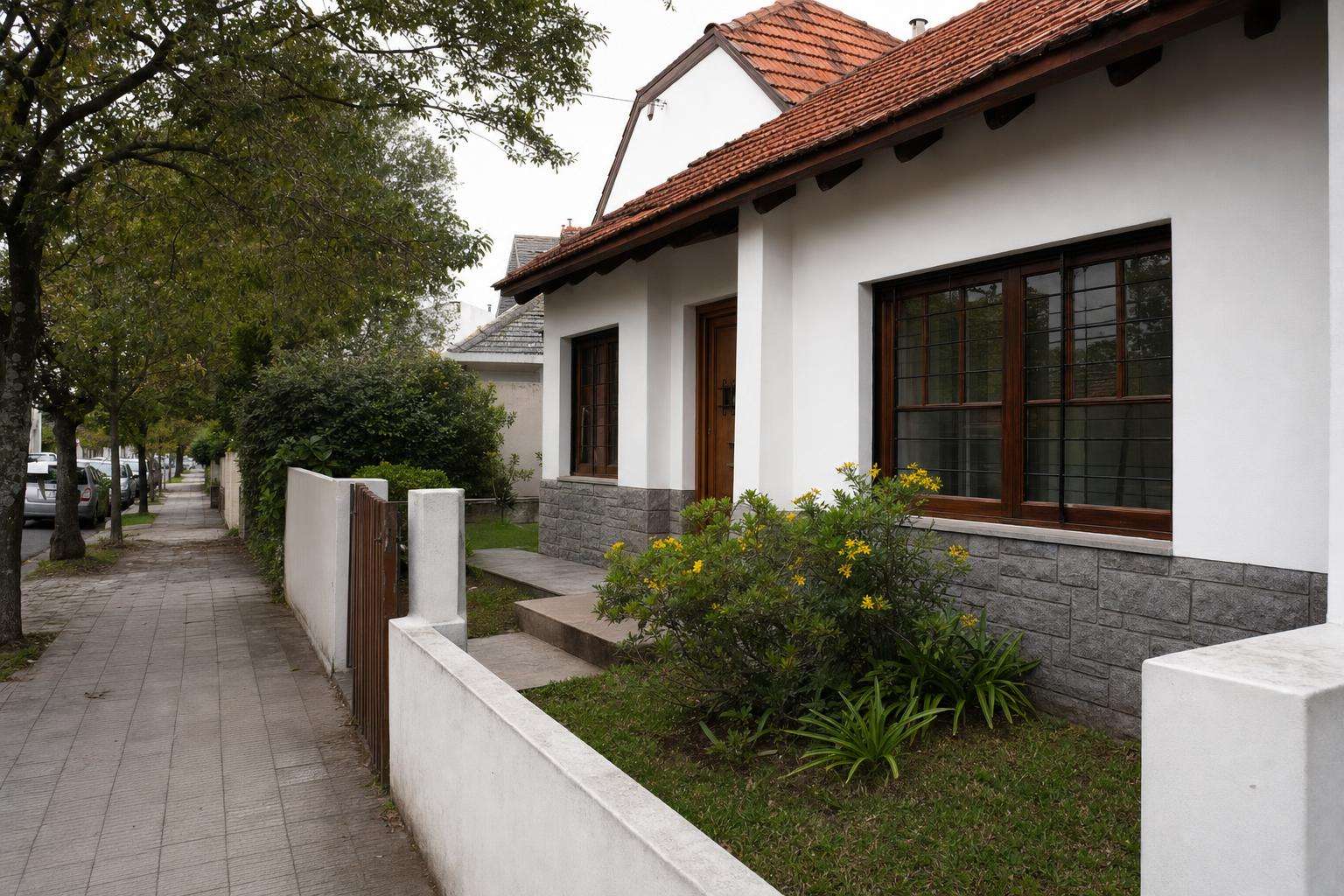 Frente de un chalet con zócalo de piedra recién pintado de blanco: pintura de frente de casa en Mar del Plata