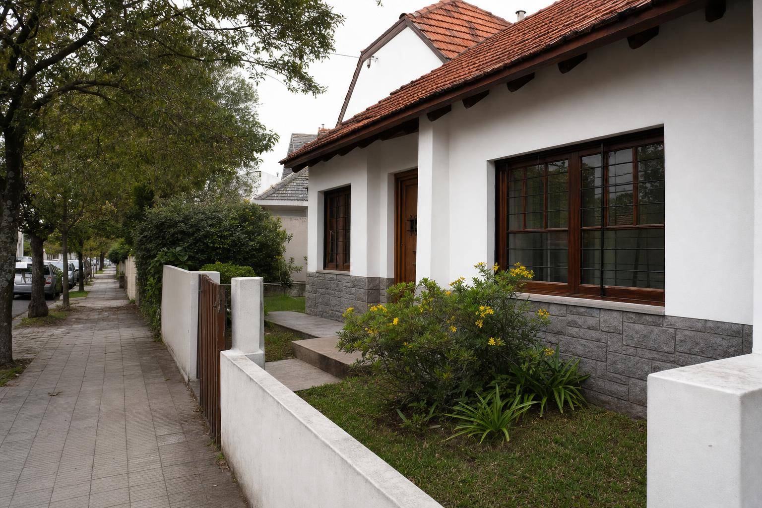 Frente de un chalet con zócalo de piedra recién pintado de blanco: pintura de frente de casa en Mar del Plata